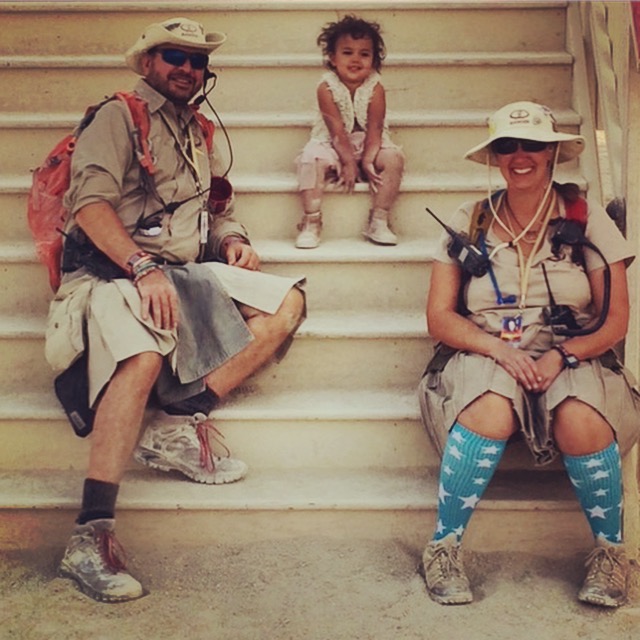 A male and female Black Rock Ranger sitting on steps with a toddler between them.